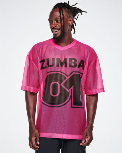 A male model wearing a pink mesh Zumba top with a large black "ZUMBA 01" printed on the front, paired with black pants.