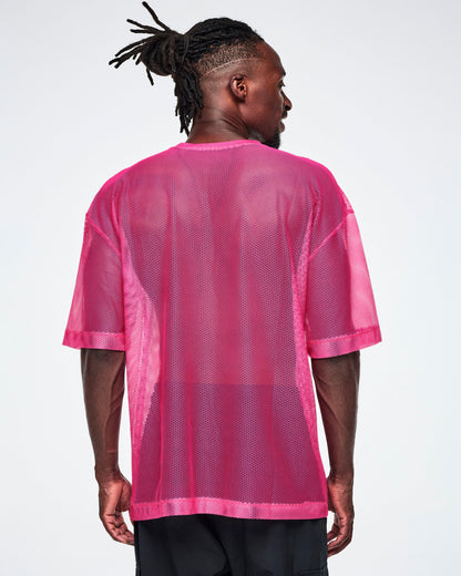 Back view of a male model wearing a pink mesh Zumba top, paired with black pants.