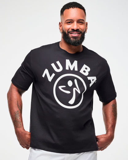 Male model in the black oversized T-shirt with white 'ZUMBA' text and a Zumbito logo, paired with white pants.