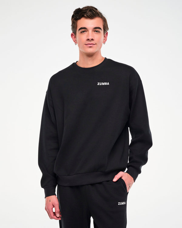 Male model in the black waffle-knit crewneck sweatshirt and matching sweatpants, one hand in his pocket.