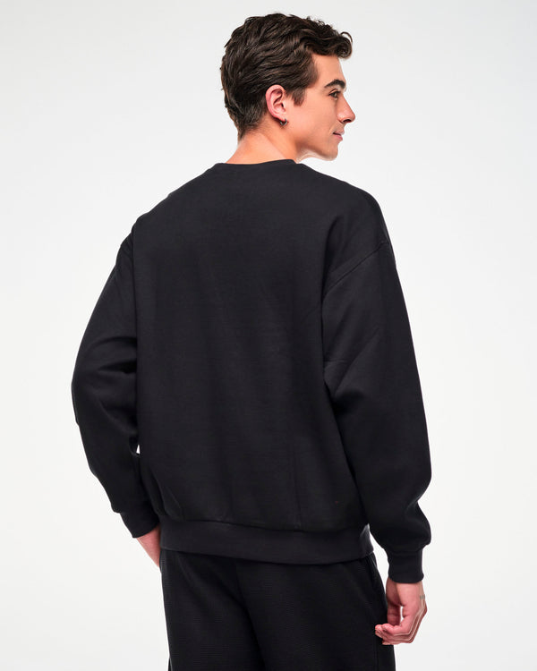 Back view of the black waffle-knit crewneck sweatshirt, male model, showing the oversized fit.