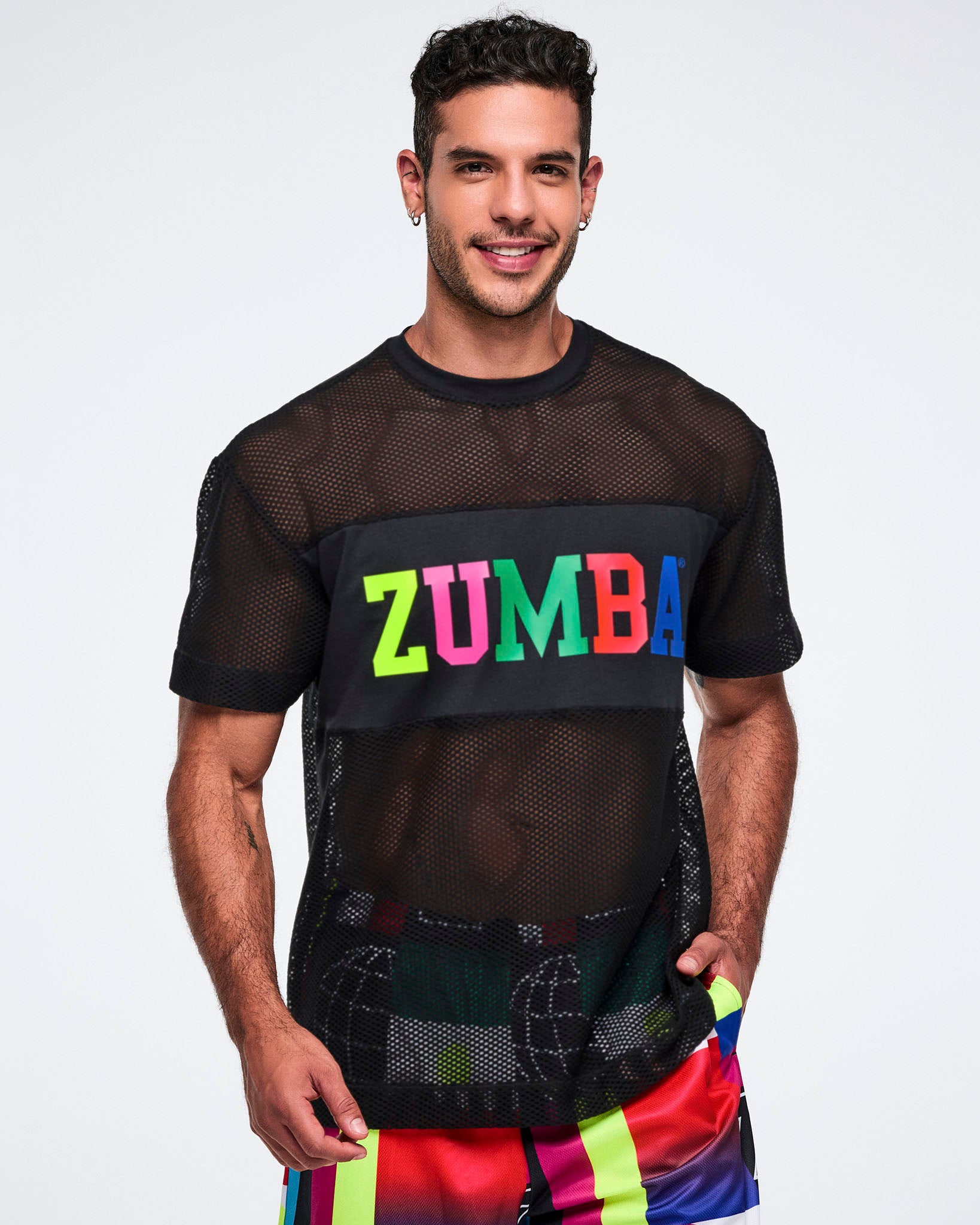 Male model wearing a black Zumba mesh shirt with colorful letters on a plain background.