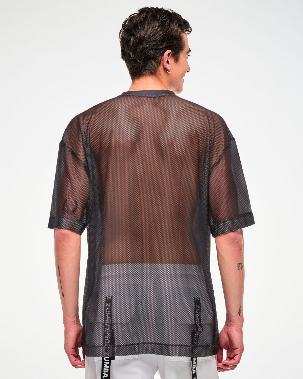 Back view of the black mesh oversized top, male model, showing the sheer mesh fabric.