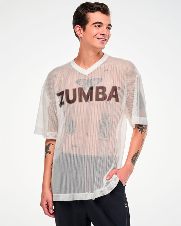 Male model in the white mesh oversized top with black 'ZUMBA' text, one hand in his pocket.
