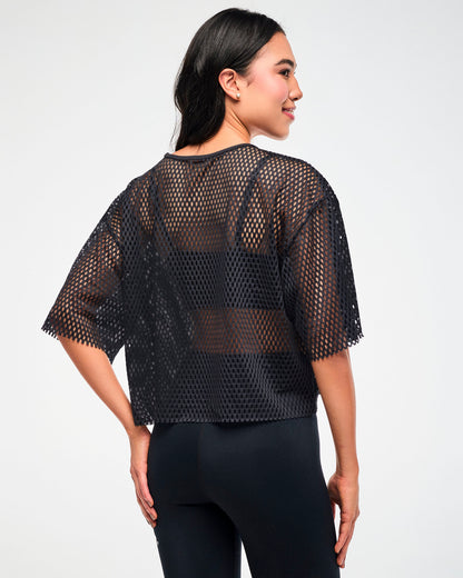 Back view of the black mesh cropped top, female model, paired with black leggings.