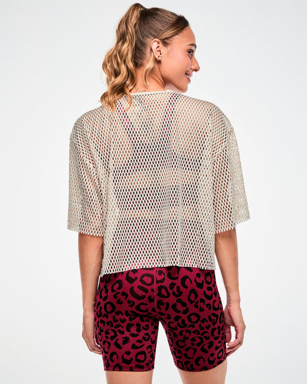 Shown from the back, a female model wears the beige mesh crop top, with the dark red leopard print bra visible through the open-hole back.