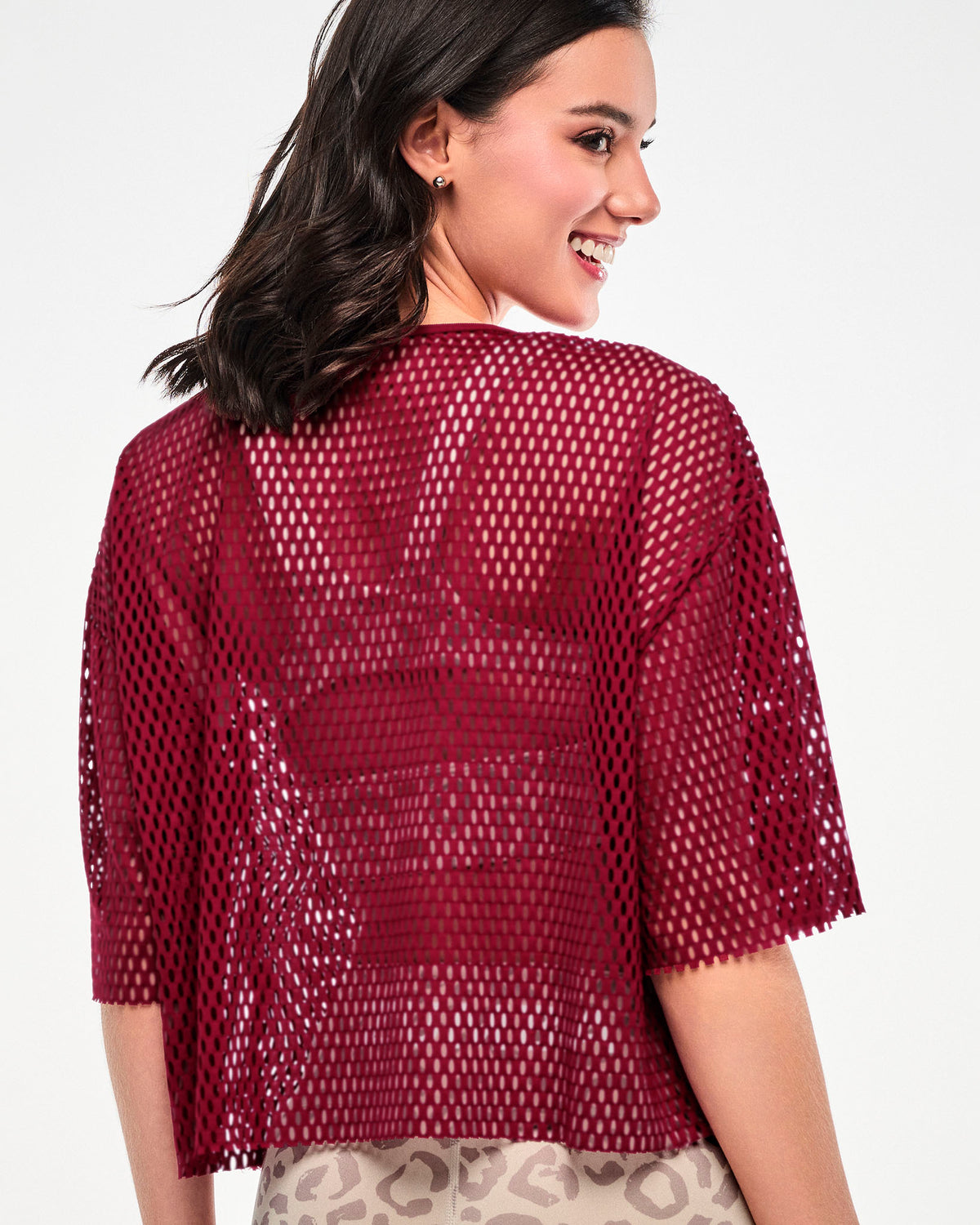 Shown from the back, a female model wears the dark red mesh crop top, showing its boxy, drop shoulder fit and raw-edge hems.