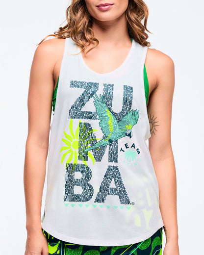 Close-up of the white racerback tank showing the “ZUMBA” text graphic with teal parrot and neon sunburst; a green sports bra is visible underneath on a female model.