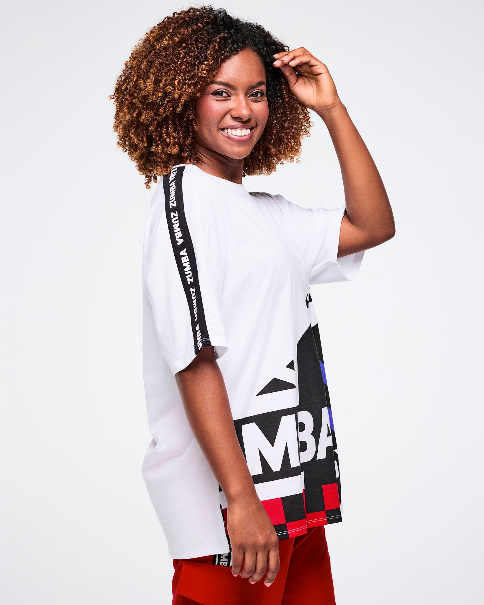 Female model viewed from the side, wearing a white t-shirt with colorful text and graphics on a plain background.