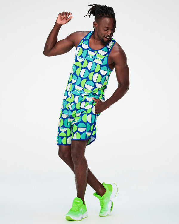 Full view of a male model in the dark blue half-circle print racerback tank with matching print shorts and neon green shoes.