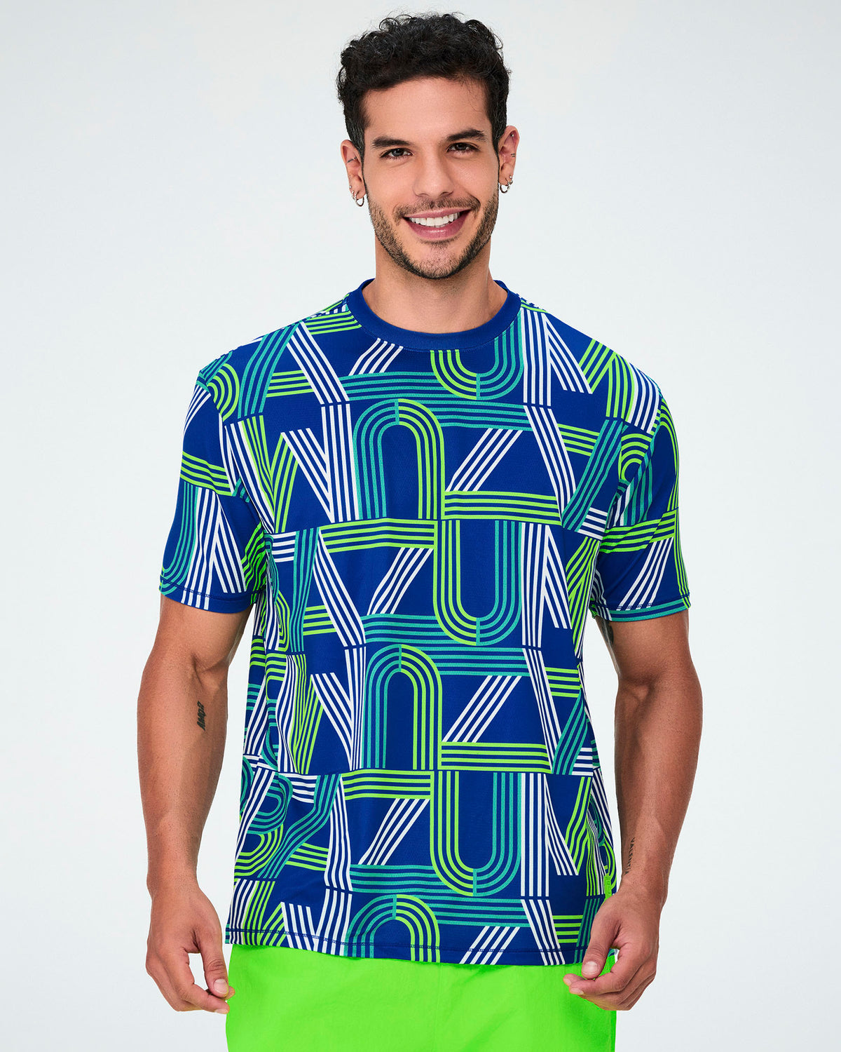 Male model in the dark blue retro striped 'ZUMBA' letter mesh top, with short sleeves, a dark blue neckband, and a straight hem over neon green shorts.