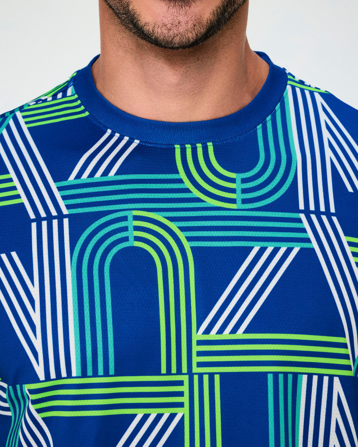 Close-up of the dark blue mesh top, showing the dark blue neckband and white, aqua, and neon green stripes forming the 'ZUMBA' letters.