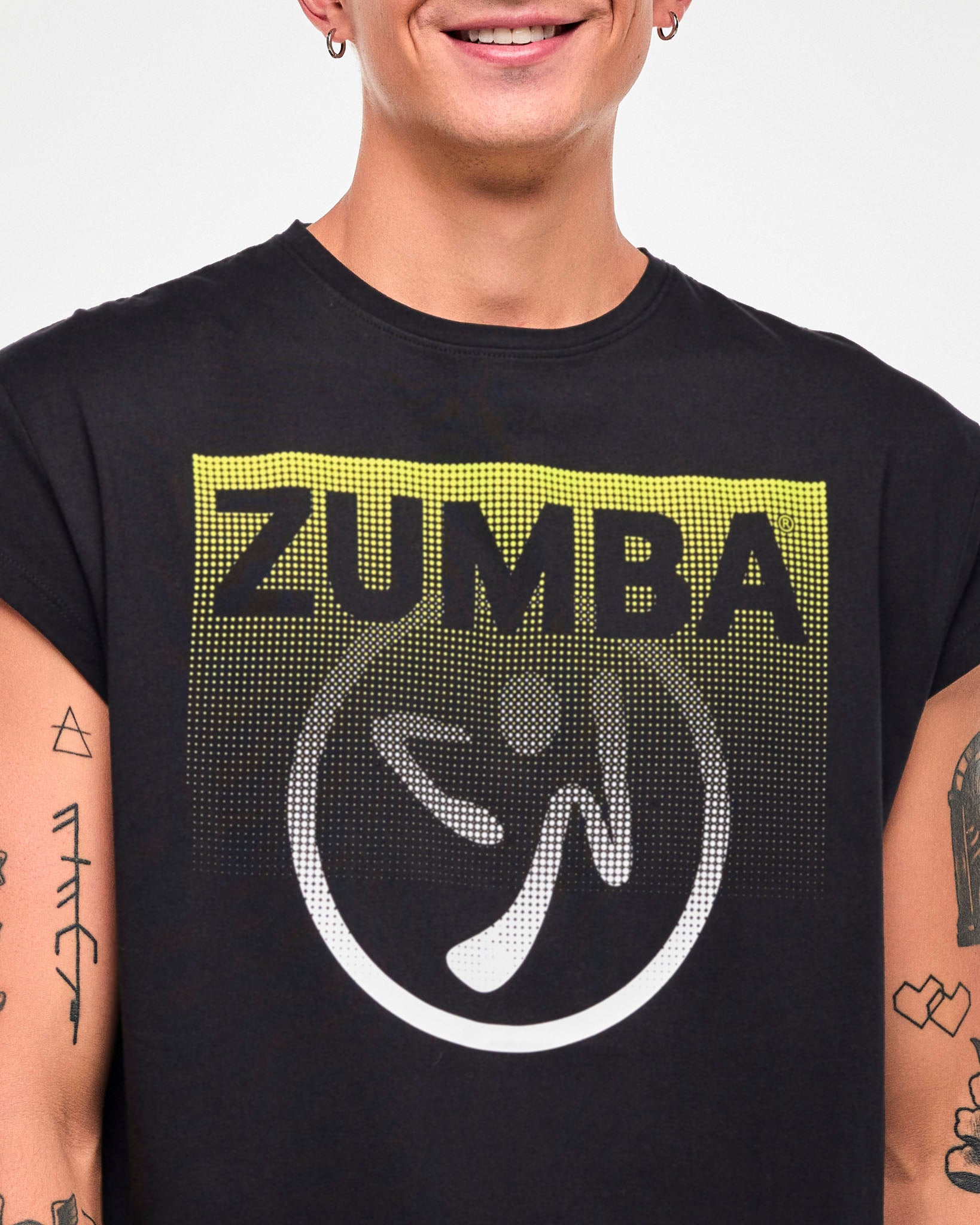 Close-up of a male model wearing a black cap-sleeve tee with a yellow-to-white gradient "ZUMBA" logo and Zumbito graphic.