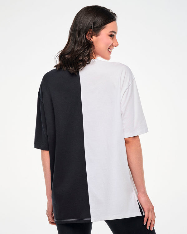 Shown from the back, female model wearing a black and white colorblock oversized T-shirt.