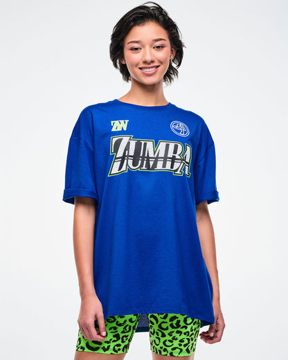 Female model wearing a blue Zumba t-shirt on a white background.