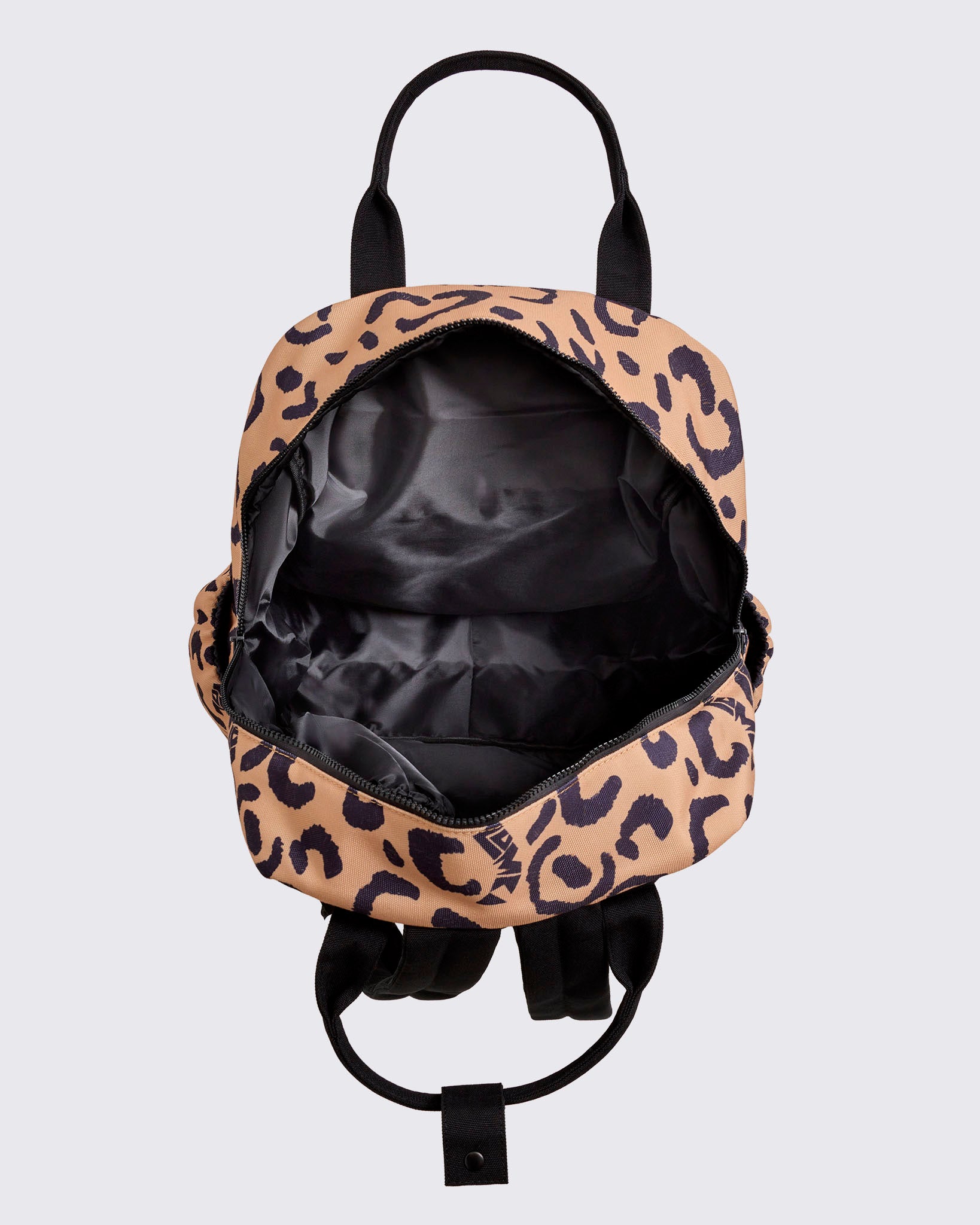 Open leopard-print Zumba backpack showing a spacious black-lined interior with a wide zip-around opening, black handles, and visible shoulder straps against a light gray background.