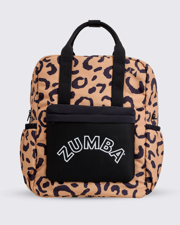 Front view of a leopard-print Zumba backpack with black top handles, side pockets, and a large black front pouch embroidered with a white ZUMBA logo against a light gray background.