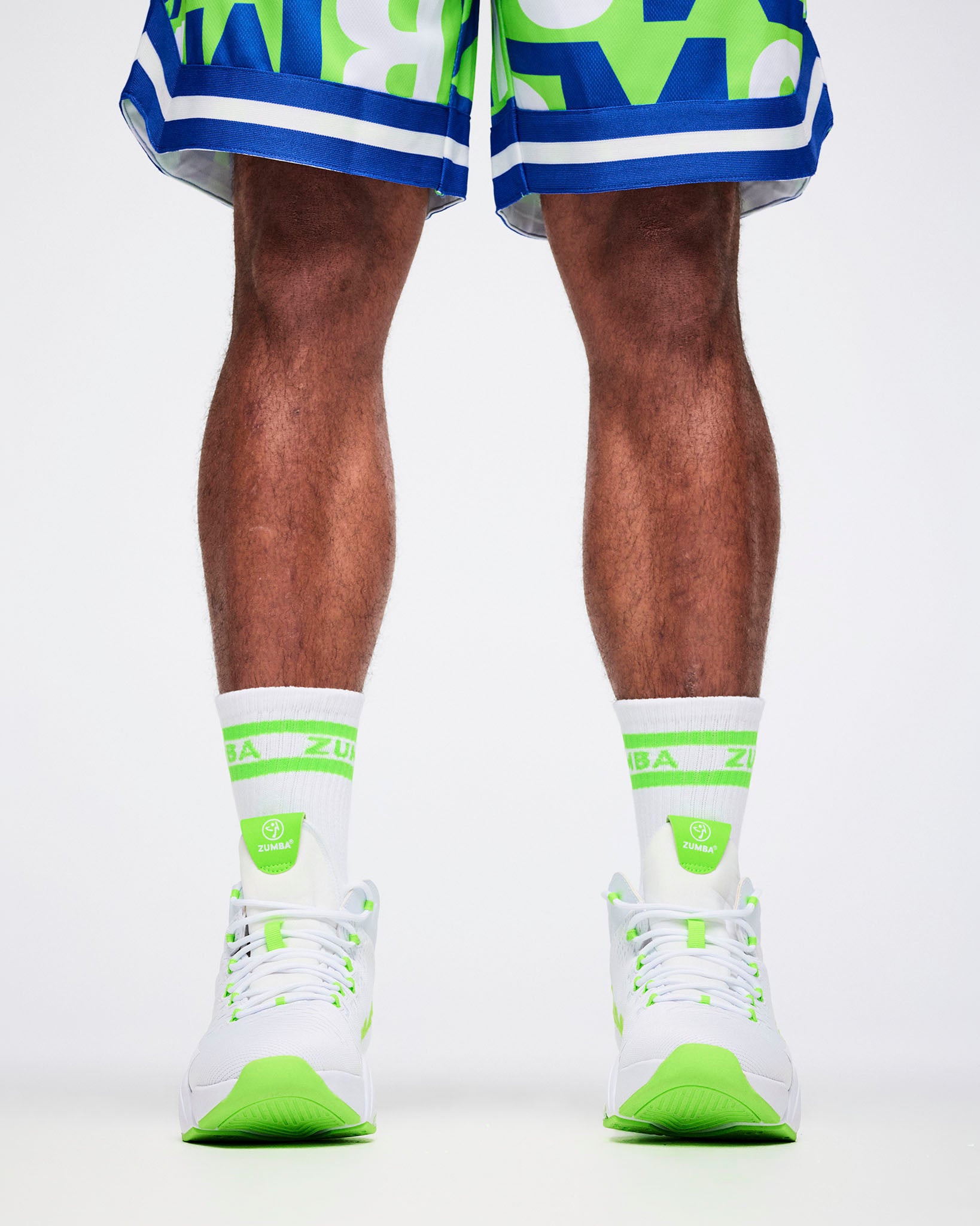 Close-up of male model in L white and green Zumba socks paired with white and green shoes.