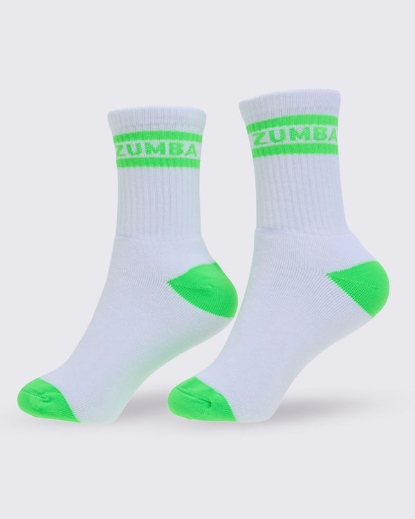 A pair of white crew socks with bright neon green accents on the toes, heels, and a double stripe with 'ZUMBA' text at the ribbed cuff, shown against a light gray background.
