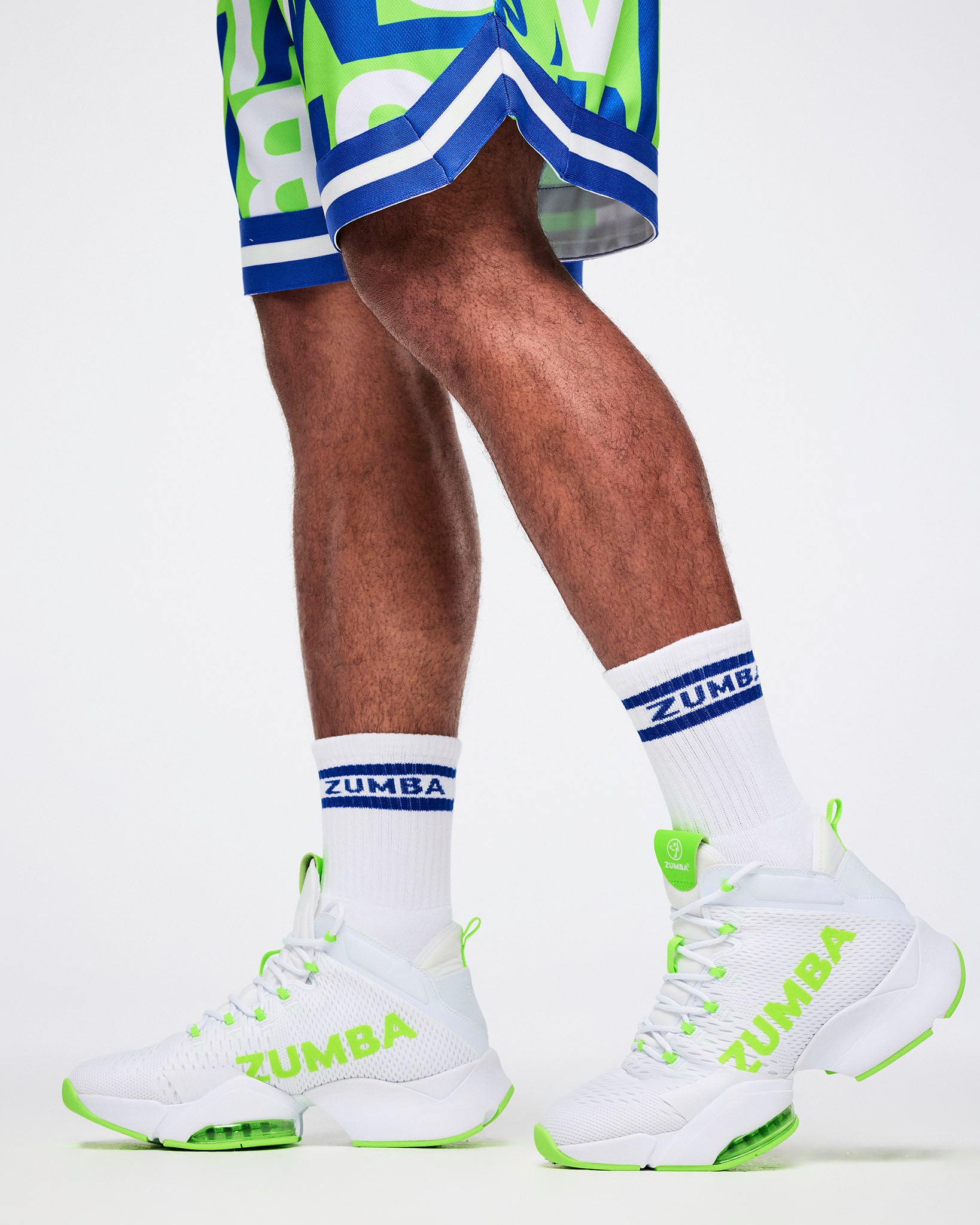 Close-up of male model in L white and blue Zumba socks paired with white and green shoes.