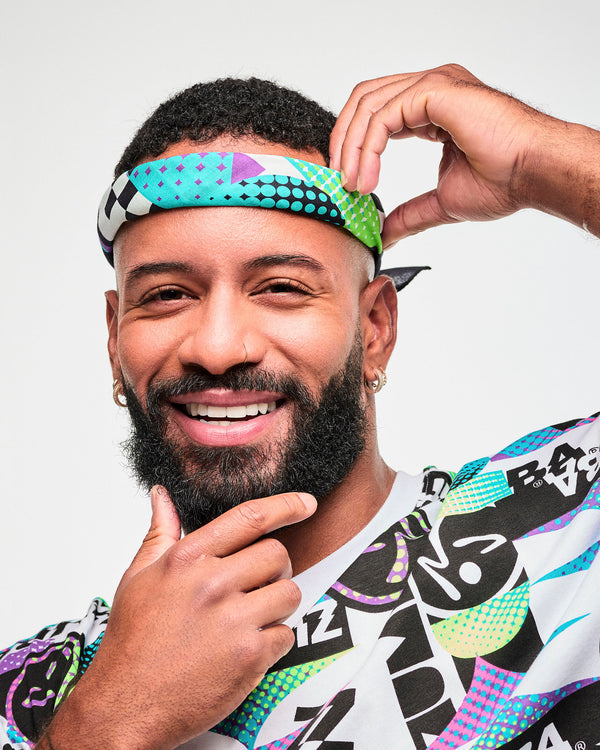 Close-up of a male model wearing a colorful printed bandana tied as a head band, paired with a matching retro-print graphic tee.