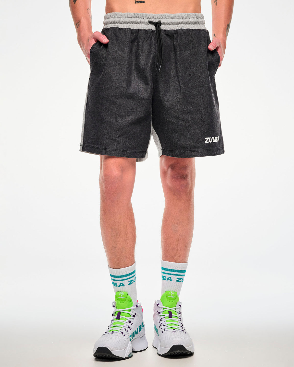 Male model wearing black and grey colorblock shorts with aqua-striped socks and white shoes.