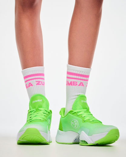 Close-up of white crew socks with pink stripes and "ZUMBA" text, paired with green shoes.