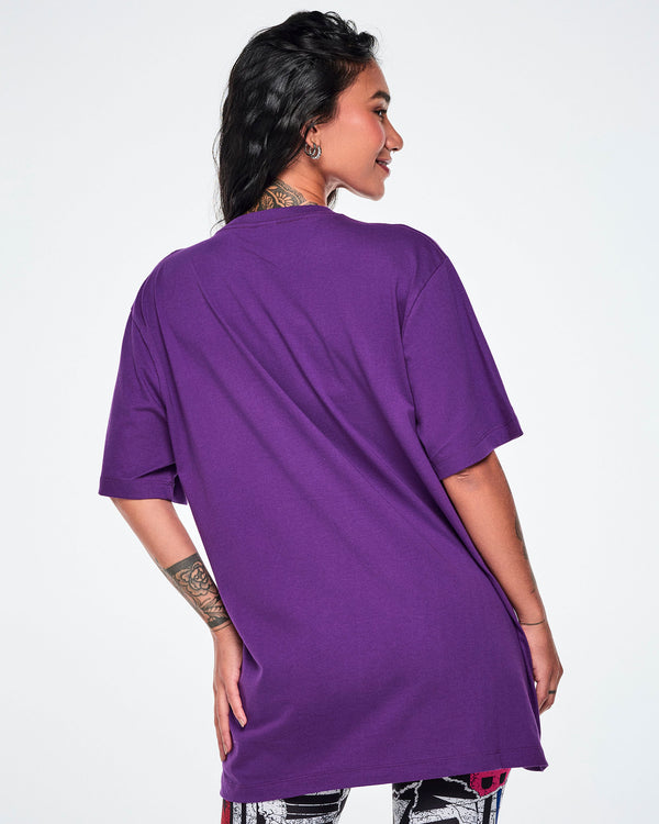 A woman shown from the back wearing an oversized purple short-sleeve tee, paired with patterned leggings.