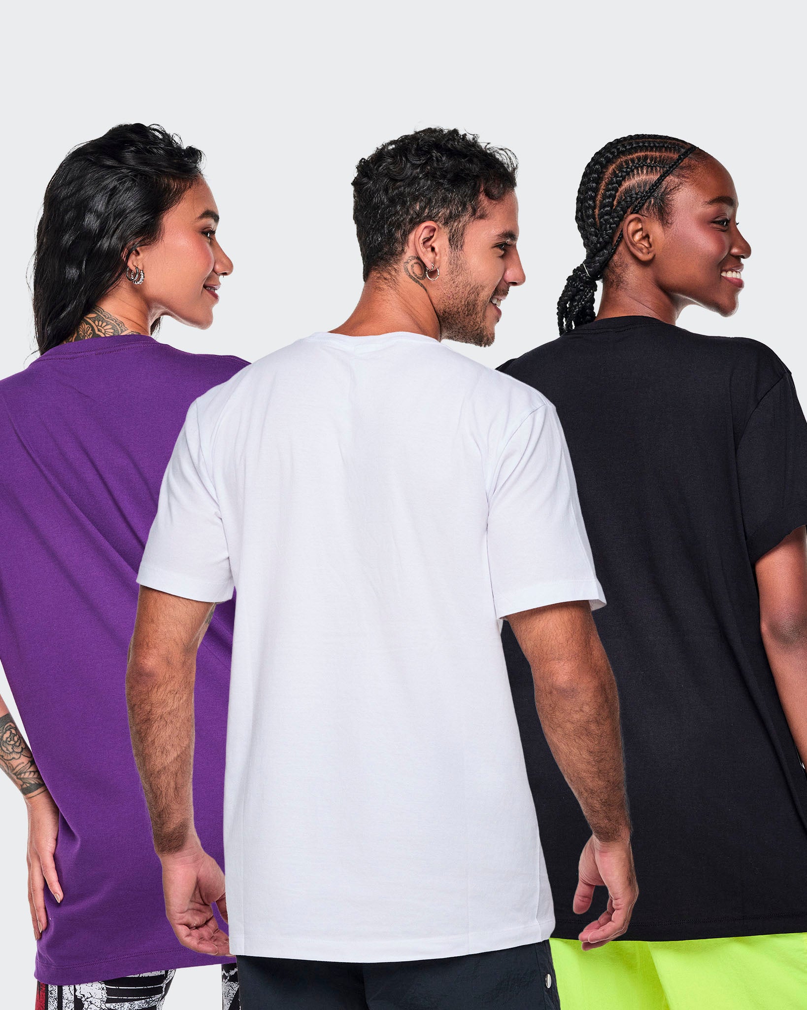 Three models shown from the back wearing plain short-sleeve T-shirts in purple, white, and black against a light white studio background.