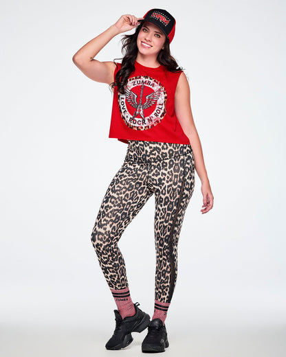 A female model modeling a red and black Zumba hat, a red Zumba rock graphic crop top, leopard-print leggings paired with black shoes.