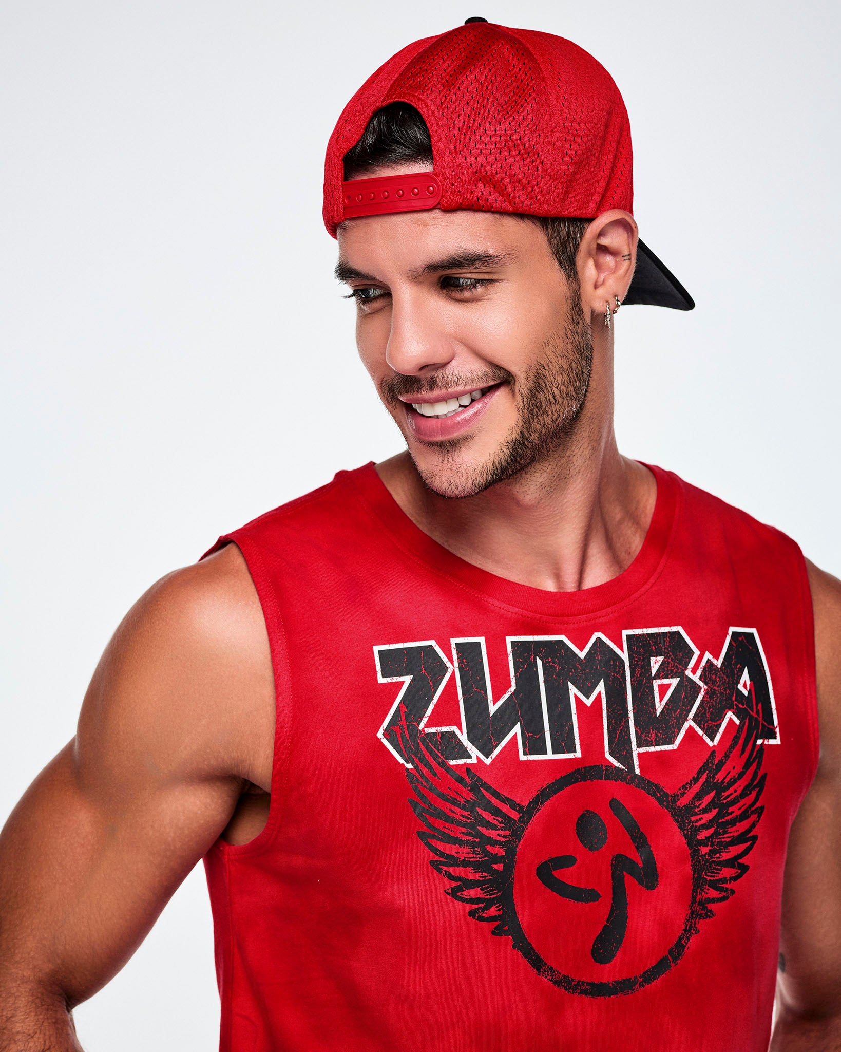 A male model wearing the a black and red hat backwards, showing the red mesh and paired with a red Zumba rock logo tank.