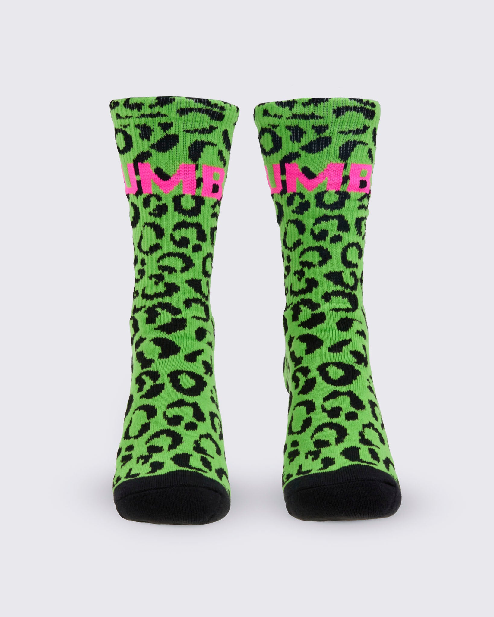 A pair of high socks, from the front, featuring a bright green and black leopard print pattern, with a pink 'ZUMBA' text on the top and solid black toes and heels, shown against a white background.
