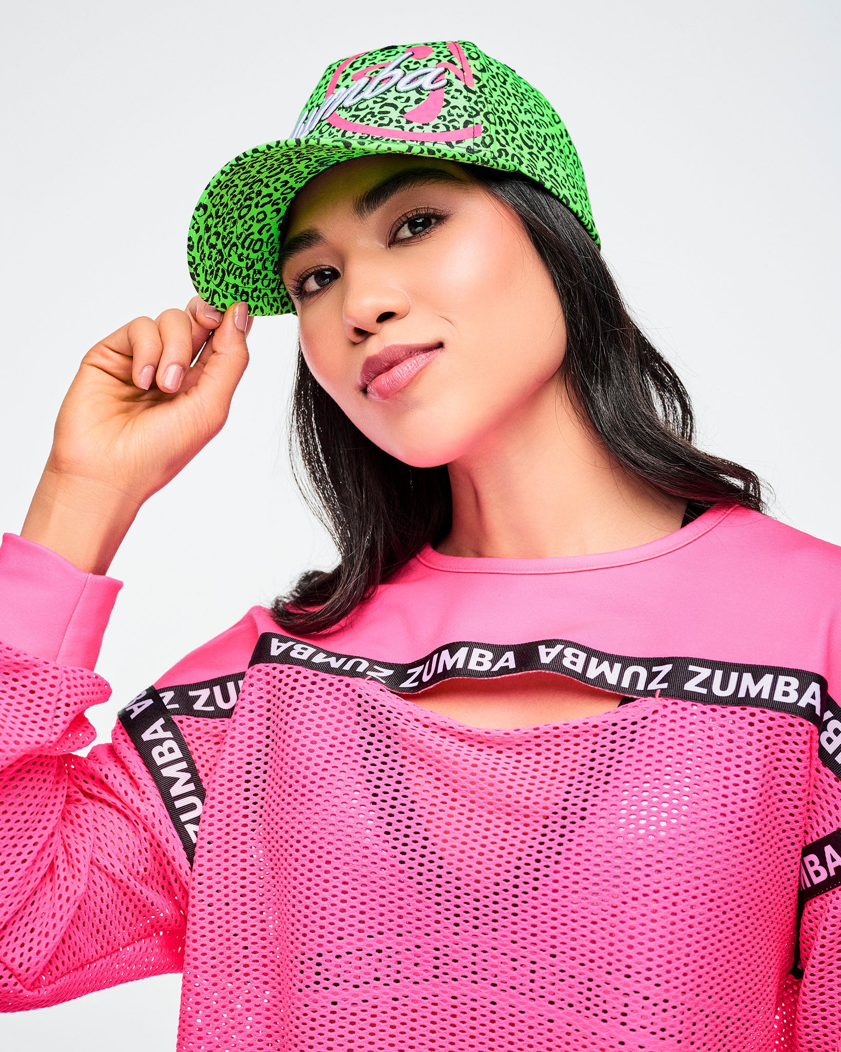 Female model wearing green and black leopard print hat and paired with a pink Zumba top.