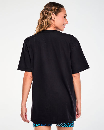 Back view of a female model in the black 'ZUMBA' and 'THE SMURFS' tee, showing a plain back and an easy, long fit.