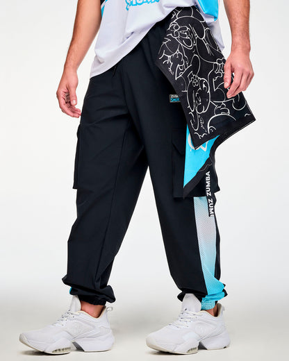 Male model holding the diagonal-split bandana at his hip, with the black side of white line-drawn Smurfs facing out and a corner of the blue side showing, over black cargo pants.