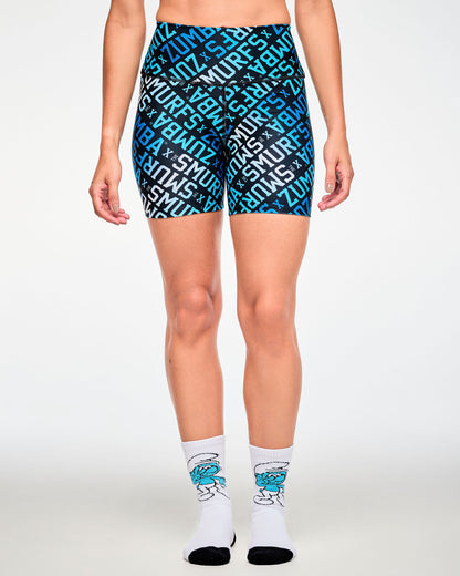 Female model wearing the Smurf crew socks with blue and white 'ZUMBA' X 'THE SMURFS' print biker shorts, the dancing Smurf showing on the front of each sock.