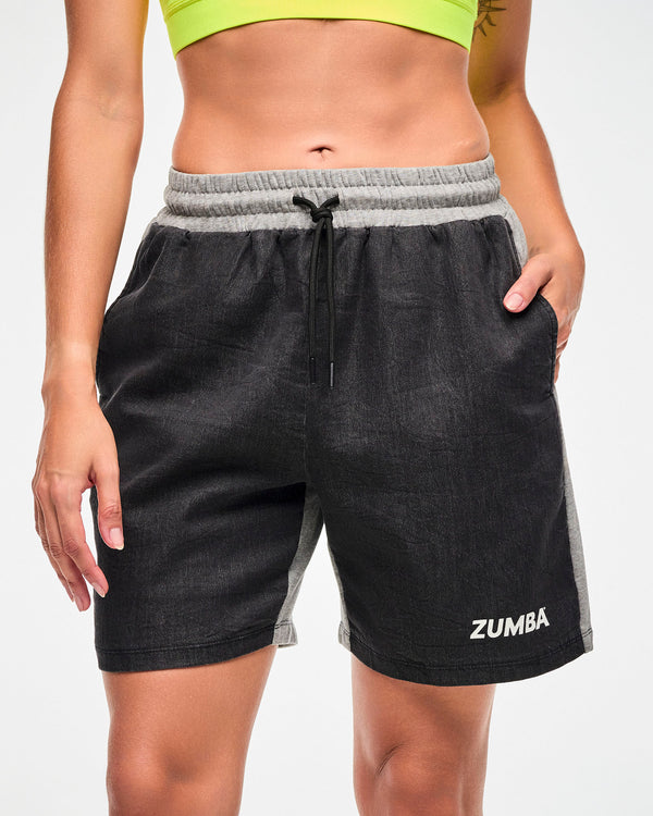 Close-up of a female model wearing black denim and grey back shorts.