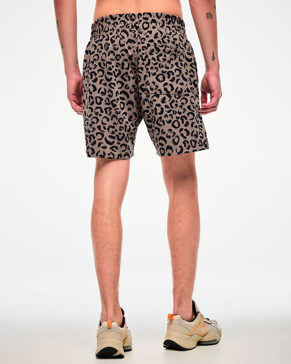 Back view of a male model in the leopard print easy shorts, showing the back patch pocket and relaxed fit, paired with beige shoes.