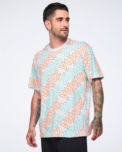 White short-sleeve Zumba T-shirt with a crew neckline and allover mint and orange diagonal logo print. Male model wears the relaxed-fit tee with black pants.
