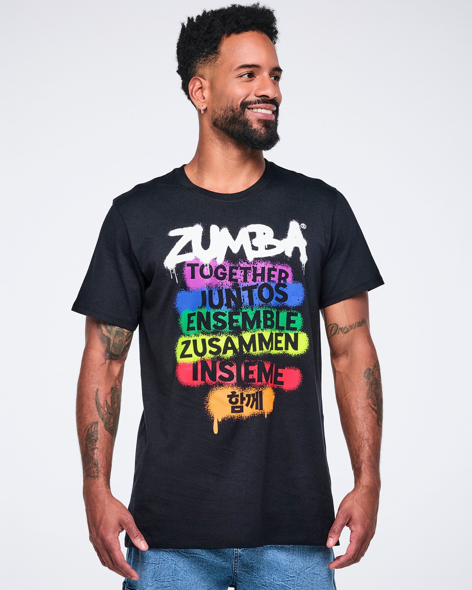 Male model wearing a black Zumba t-shirt with colorful text on a white background.