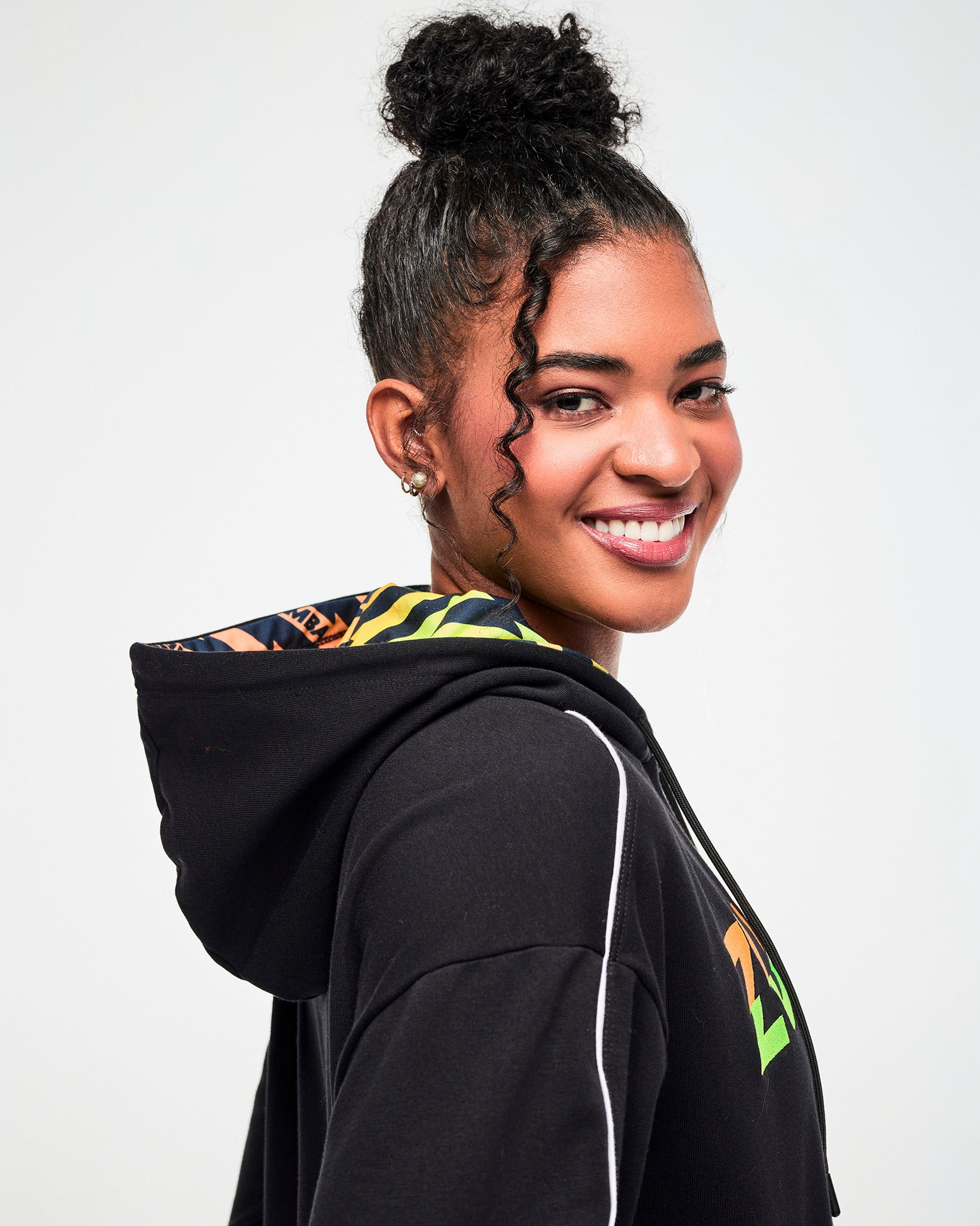Close-up of a female model showing the orange, yellow, and green ombre lightning bolt-print hood lining.