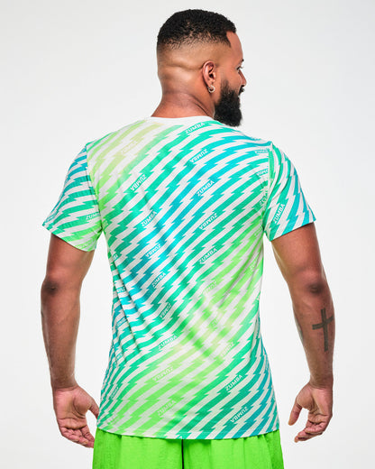 Male model wearing a green and aqua lightning bolt-striped tee with "ZUMBA" text, paired with lime green pants, viewed from the back.