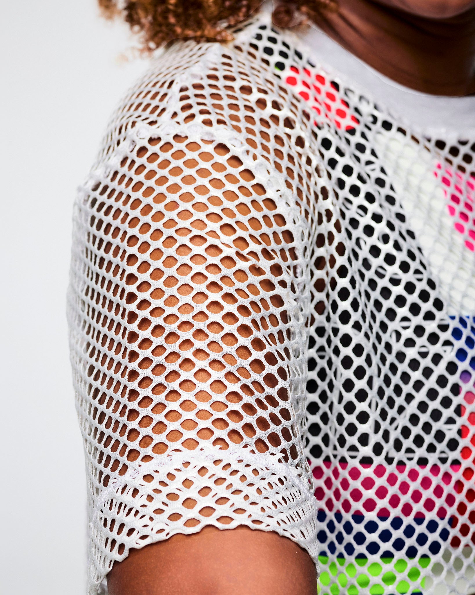 Close-up of a female model wearing a white mesh top, highlighting the mesh’s texture and detail.