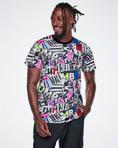 A male model wearing a multi-colored ZUMBA graphic tee and black pants.