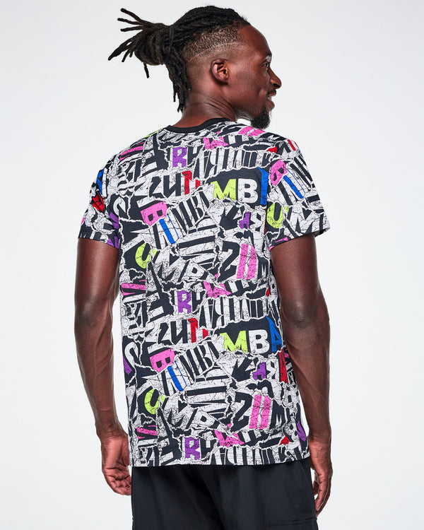 Back view of a male model wearing a multi-colored ZUMBA graphic tee and black pants.