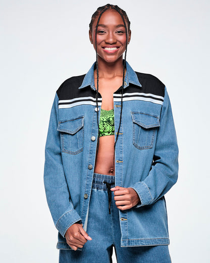 Front view of a female model wearing an open denim shacket with a black yoke featuring white stripes across the shoulders, layered over a neon green snake-print bra top, with visible chest pockets.