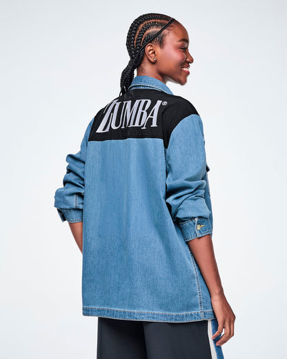 Back view of a female model wearing a denim shacket with a black yoke featuring white "ZUMBA" text, paired with black pants.