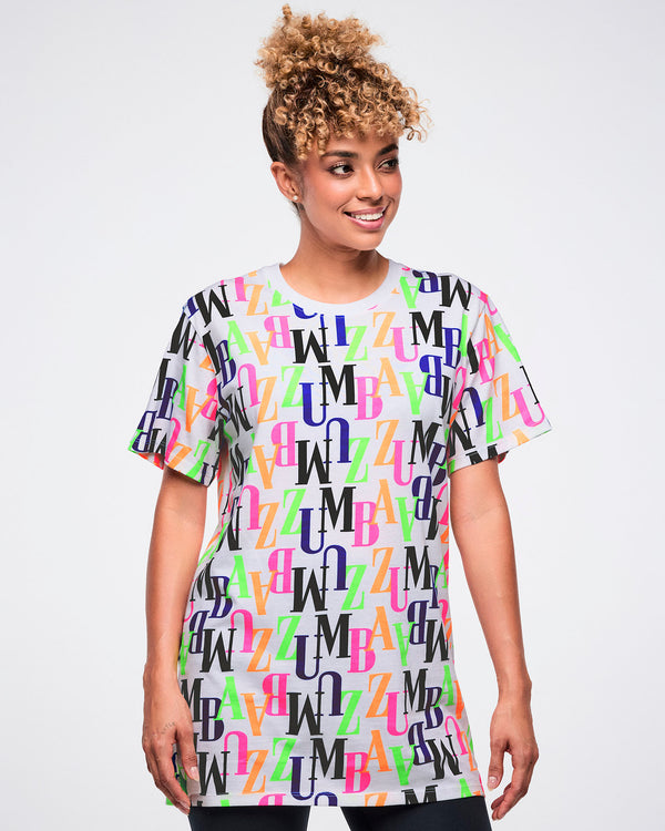 Female model wearing a colorful 'ZUMBA' patterned t-shirt against a white background.