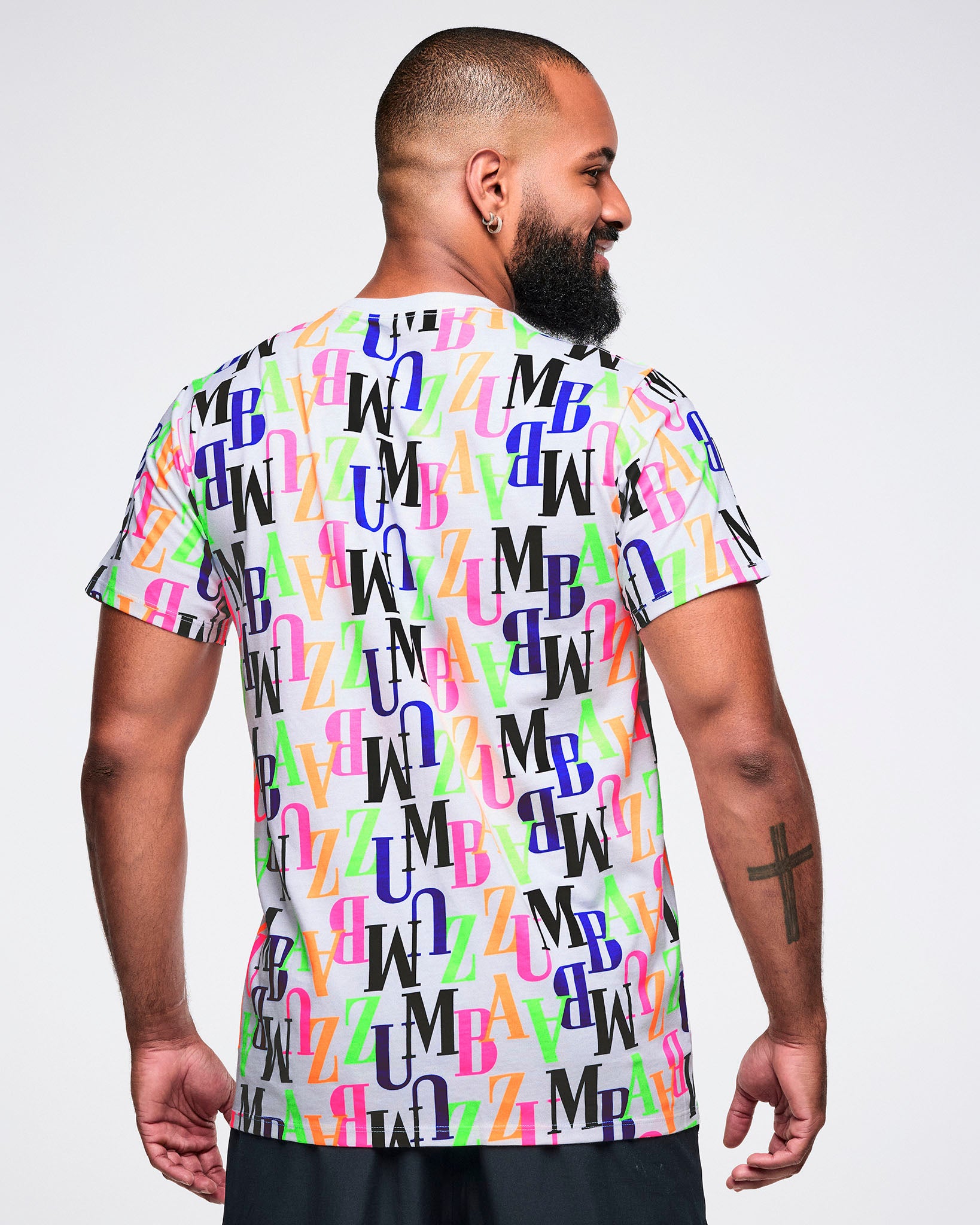 Back view of a male model wearing a colorful 'ZUMBA' patterned t-shirt and black shorts.