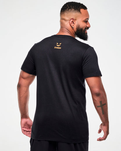 Shown from the back, male model wearing a black tee with a small orange jack-o'-lantern graphic and "ZUMBA" text.
